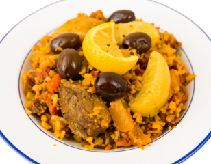 Hearty baked rice with tender meat chunks black olives and bright lemon wedges.