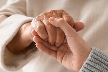 Senior woman with caregiver holding hands, closeup. Care concept