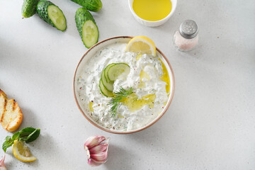 Tzatziki salad in white bowl on white background. Homemade Tzatziki salad with olive oil and copy space. Top view.