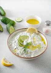 Tzatziki salad in white bowl on white background. Homemade Tzatziki salad with olive oil.