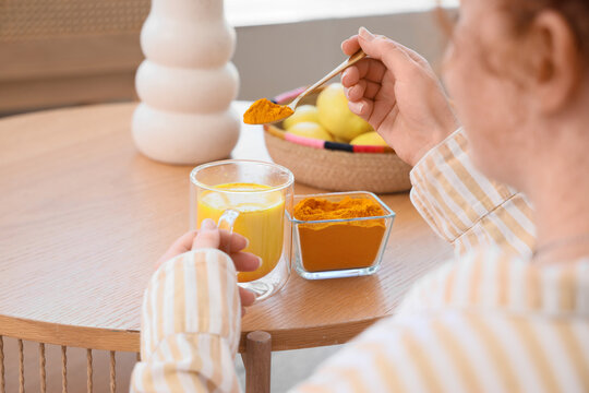 Young woman making turmeric drink at home, closeup