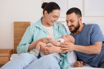 Obraz premium Happy parents with their little baby sitting in bedroom