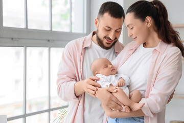 Happy parents with their little baby near window at home