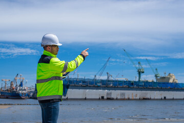 A specialist technician at a shipping port is inspecting the structure of the port and cranes to ensure they are still strong and usable.