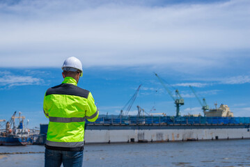 A specialist technician at a shipping port is inspecting the structure of the port and cranes to ensure they are still strong and usable.