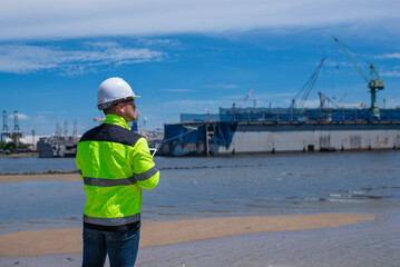 A specialist technician at a shipping port is inspecting the structure of the port and cranes to ensure they are still strong and usable.