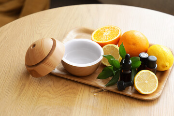 Air humidifier with essential oils and citruses on table in room, closeup