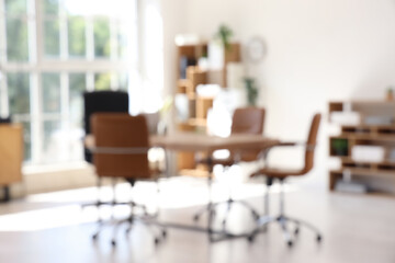 Blurred view of conference hall with table, shelf units and plants