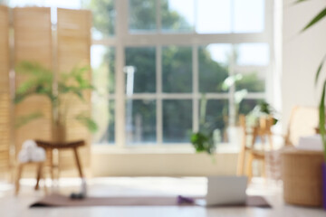 Blurred view of gym with sports equipment, armchair and palm plants