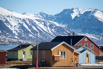 Colorful buildings at the base of snow covered mountans in the research base at Ny Alesund, Svalbard, Norway © Angela