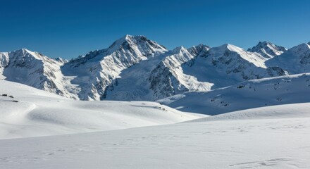 Obraz premium A breathtaking winter landscape featuring majestic snow-covered mountain peaks under a clear deep-blue sky, with untouched snowfields stretching across the foreground.