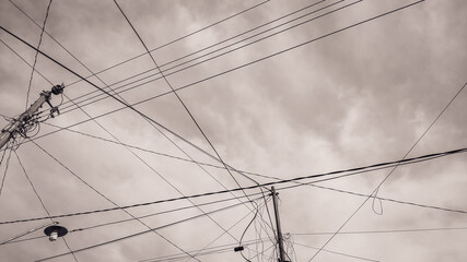 High voltage electricity pole standing tall against a dramatic cloudy sky, showcasing industrial...