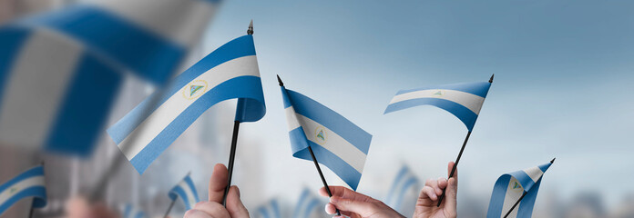 Nicaragua flags in their hands on a blurred urban background