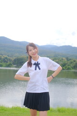 Fototapeta premium A girl in a school uniform poses for a picture by a lake. A Student girl concept