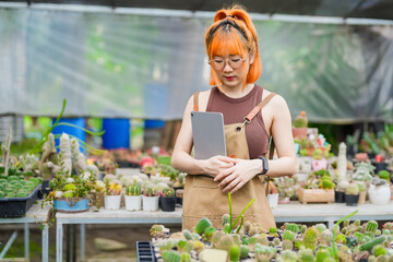 Young Asian Woman Working in Greenhouse Farm as Eco Business Owner with Tablet in Cactus Shop