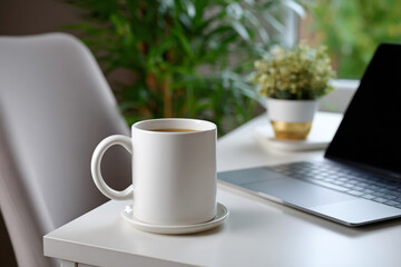 Coffee Mug and Laptop on White Desk for Remote Work Concept