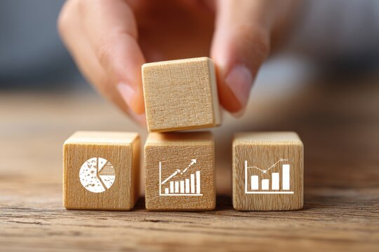 Hand placing wooden block with graph icon atop a stack of similar blocks