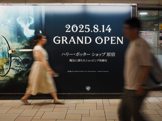 Naklejka premium TOKYO, JAPAN - August 13, 2025: People passing a billboard in Omotesando subway station advertising a new Harry Potter Shop in Harajuku.