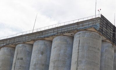 Row of Industrial Concrete Grain Silos Under Cloudy Sky