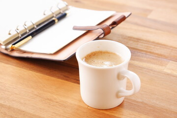 Opened schedule planner, diary, notebook with cup of Coffee on table
