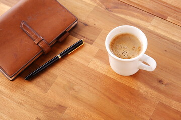 Brown schedule planner, diary, notebook with cup of Coffee on table
