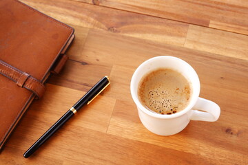 Brown schedule planner, diary, notebook with cup of Coffee on table
