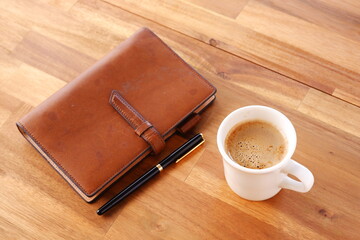 Brown schedule planner, diary, notebook with cup of Coffee on table
