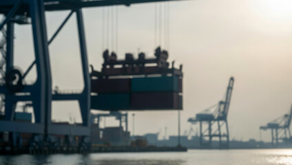 Obraz premium Shipping containers being lifted by a crane at a busy port, capturing the dynamic movement and heavy machinery used in global trade and logistics.