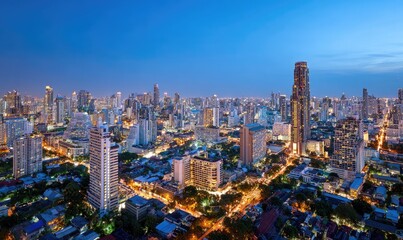 Fototapeta premium Panoramic city skyline at twilight. Dense urban sprawl of high-rises and streets. Soft, illuminated buildings against a clear blue-toned sky