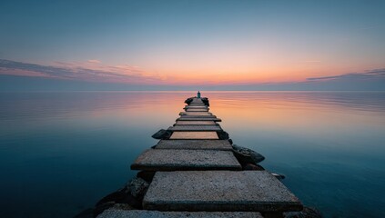 Serene sunset over calm sea; lone figure stands at end of long, stone jetty extending into tranquil waters, reflecting pastel sky