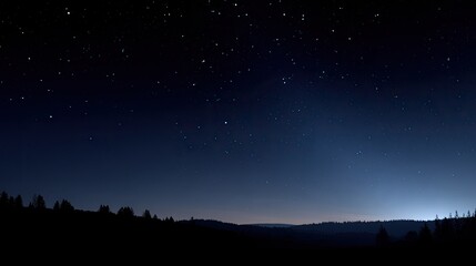 Naklejka premium Starry night sky over a dark mountain range. Silhouette of distant trees. Pale light along horizon