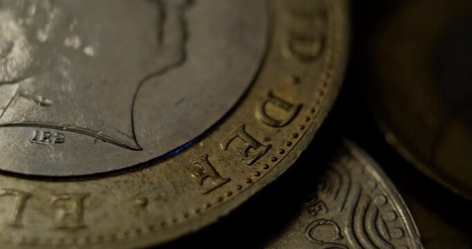 Detailed macro view of a British pound coin showing engraved letters and textures under moody lighting.