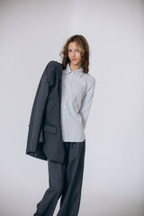 A teenage girl model is young and beautiful in a business suit and shirt in a studio on a white background