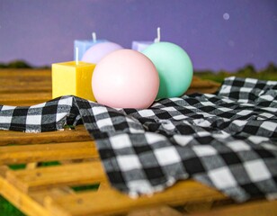 Candles in a Cozy Arrangement: A charming still-life composition of colorful candles, a checkered tablecloth, and a wooden surface create a warm and inviting atmosphere.
