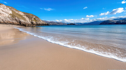 Fototapeta premium Serene sandy beach with gentle waves lapping at shore, surrounded by hills and mountains