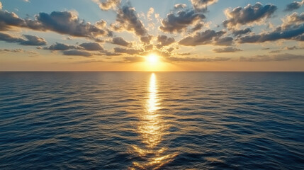Obraz premium Sunset over ocean with clouds reflecting on water, creating serene atmosphere