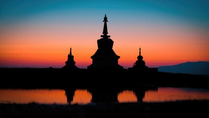 Silhouette of Buddhist stupas at sunset with reflection
