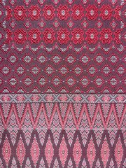 Traditional hand sewn ethnic fabric cloth in random decorative ornamental pattern, in red, pink, and purple color. Seamless background texture.