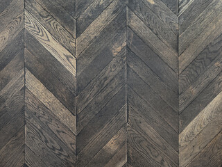 Obraz premium Dark wood flooring in chevron pattern. Dark grey oak wood in inverted chevron shape arrangement. Seamless background texture.