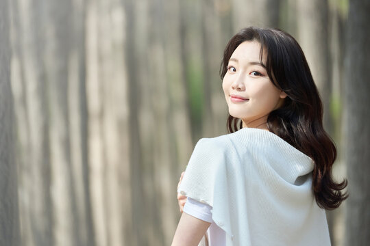 Young adult female with long wavy hair walking in a sunlit forest