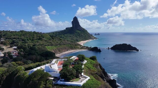 Drone captura o Forte de Noronha e a linha costeira, com contraste entre o mar turquesa e o verde da ilha.