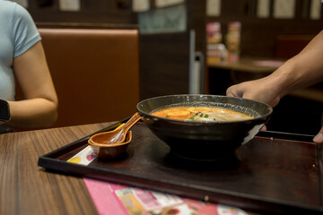 Waiter is serving food to customers at tables in a restaurant
