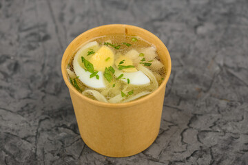 Soup with vermicelli and boiled egg in a disposable container