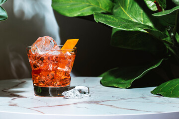 Red alcoholic cocktail drink with whiskey, gentian bitters, vermouth and orange. Marble table in...