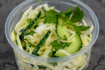 fresh cabbage salad with cucumber in a transparent disposable plate macro photo