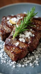 Two grilled steaks topped with rosemary and salt