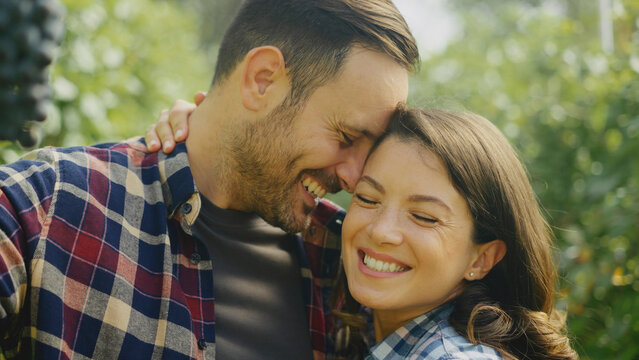 Winegrowers couple embracing and smiling in vineyard during harvest