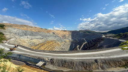 Majestic terraced quarry under azure skies, echoing serene, geological symphony, Earth Science Week, buried secrets of landscapes