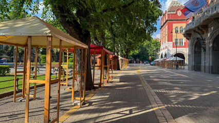 Fototapeta premium Sunlit cobblestone path with empty stalls evokes post-festival quietude, ideal for Midsummer's Night trance or Dia de Feria
