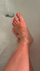 Fototapeta premium Soothing splash on pale Caucasian feet, serene bathtub meditation, daily ritual rejuvenation, celebrates National Relaxation Day vibes